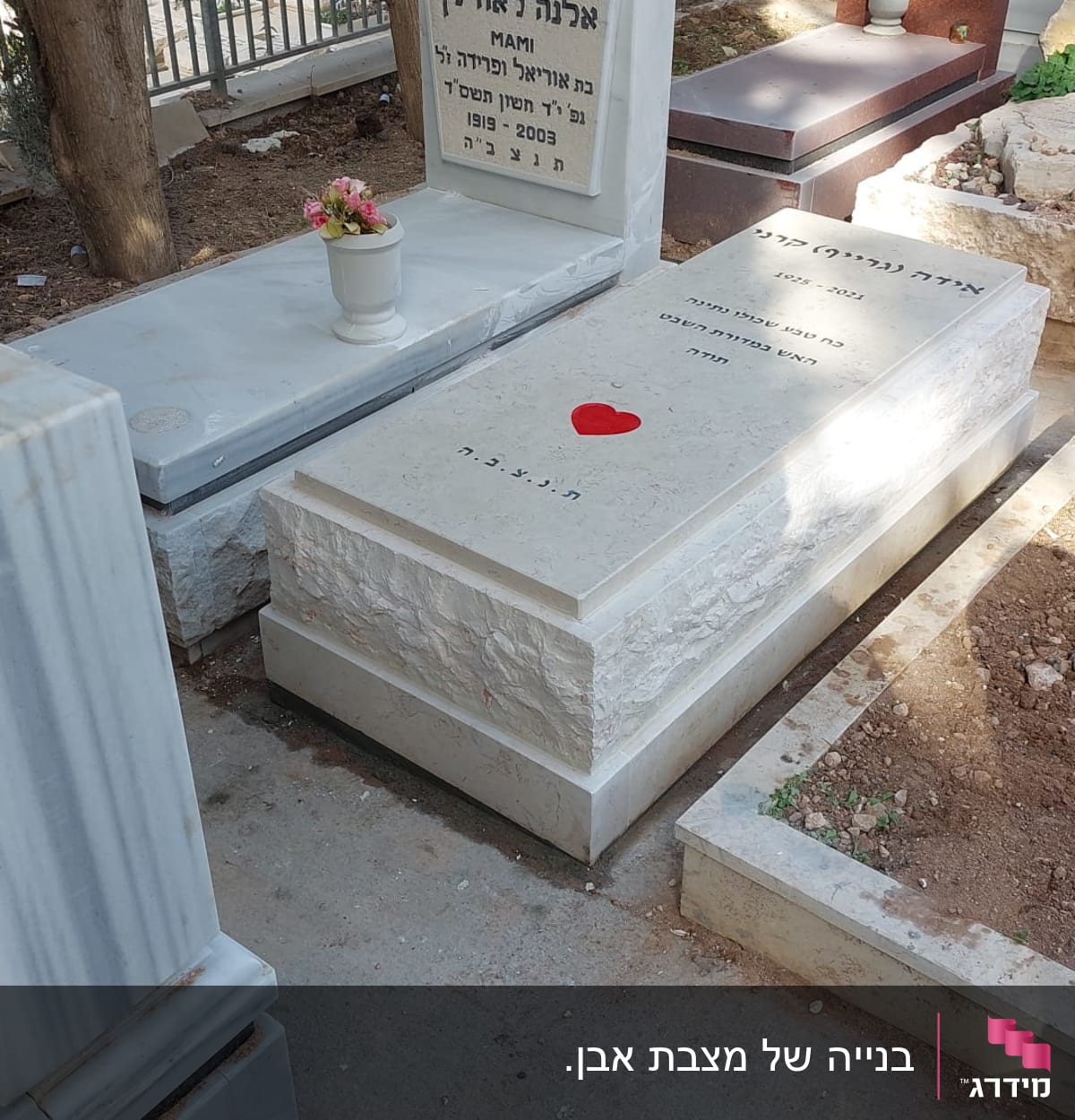 מצבות עם כיתוב בעברית ופרחים על אחת מהן